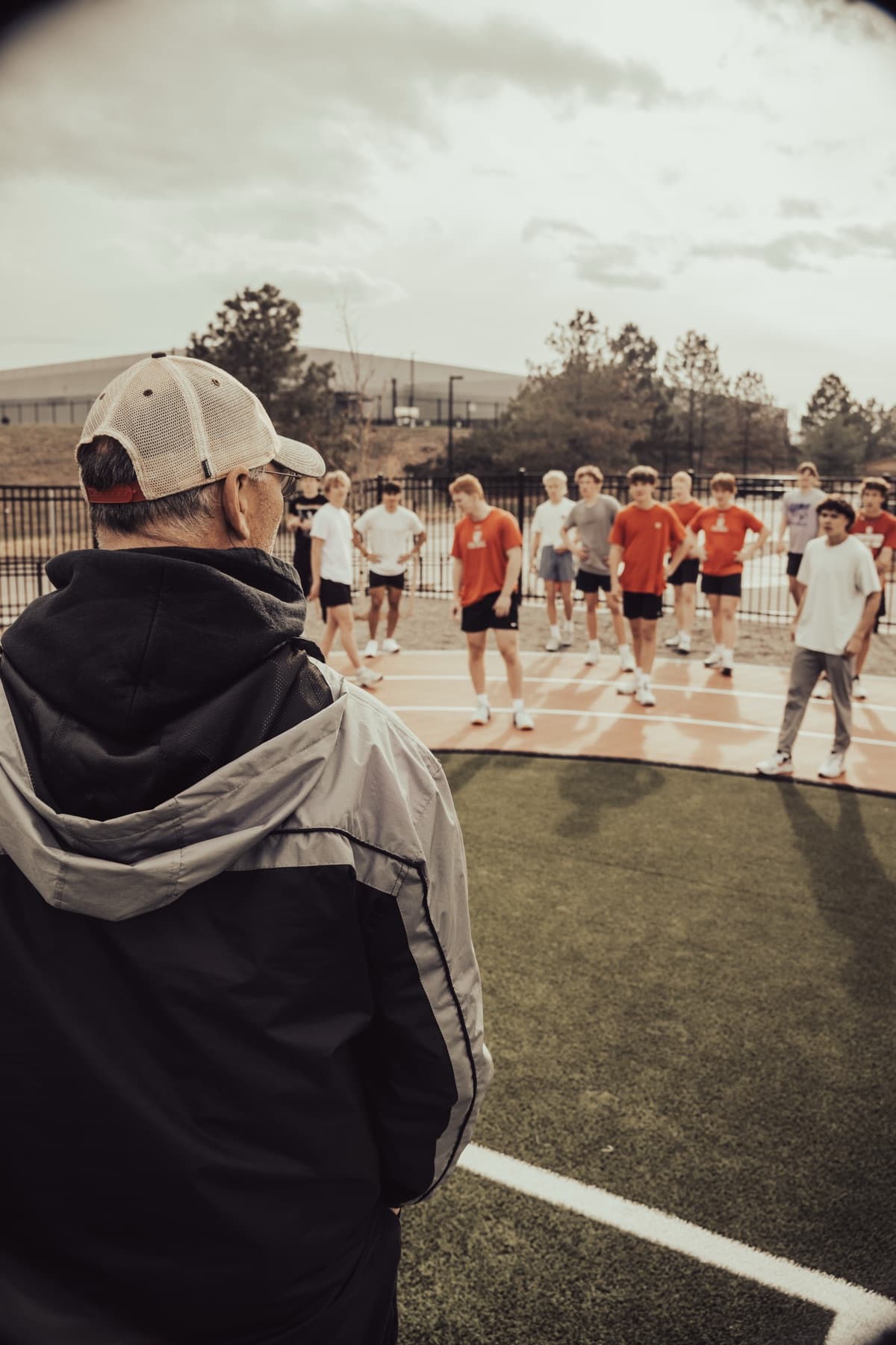 A coach speaking with athletes on a turf field